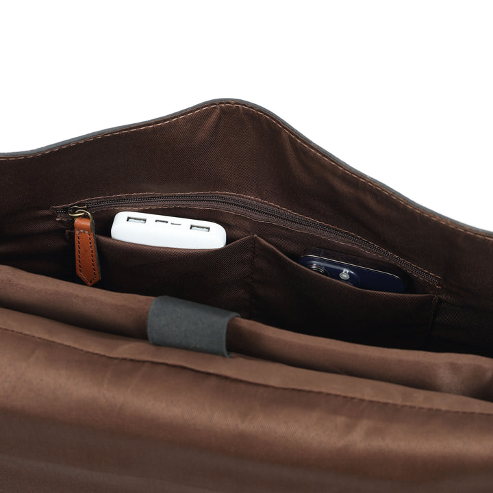 Brown leather bag with a USB drive and smartphone inside on a white background