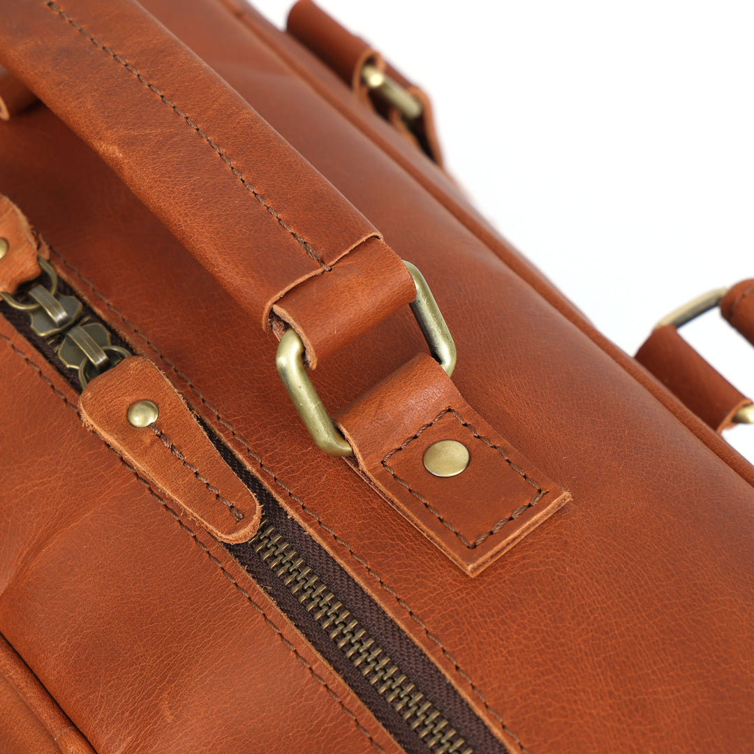 Close-up of a brown leather bag with gold zipper and hardware.