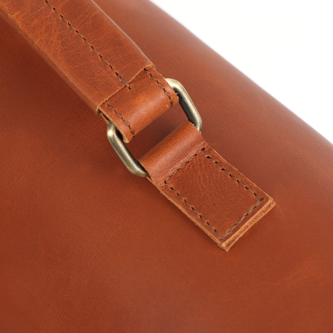 Close-up of a brown leather bag with a gold buckle on a white background