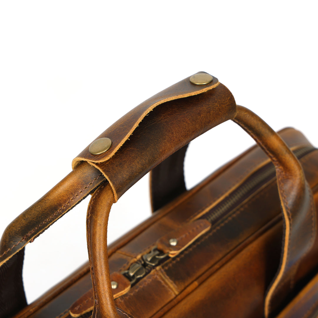 Close-up of a brown leather briefcase with gold studs on a white background