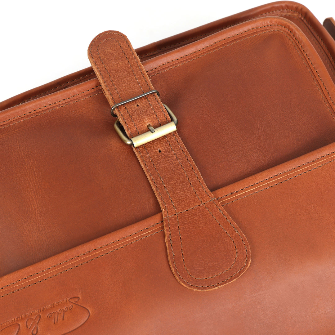 Close-up of a brown leather bag with a strap and visible brand logo.