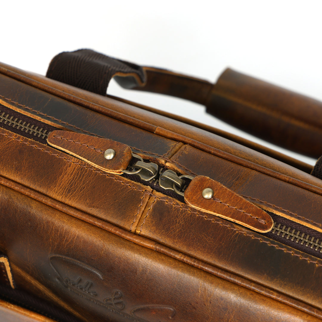 Close-up of a brown leather briefcase with a visible brand logo.