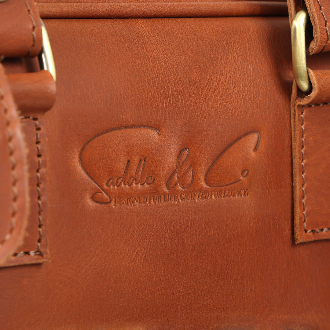 Close-up of a brown leather bag with 'Saddle & Co.' branding.