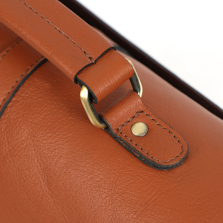 Close-up of a brown leather bag with a gold buckle and button.