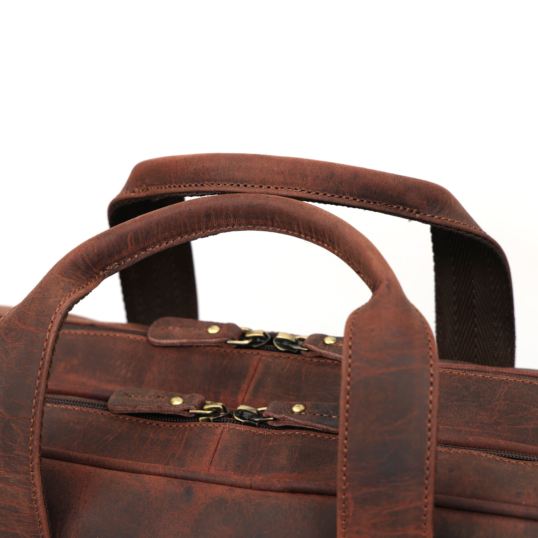 Brown leather briefcase with handles and a strap on a white background