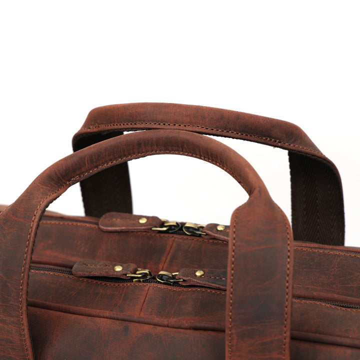 Brown leather briefcase with handles and a strap on a white background
