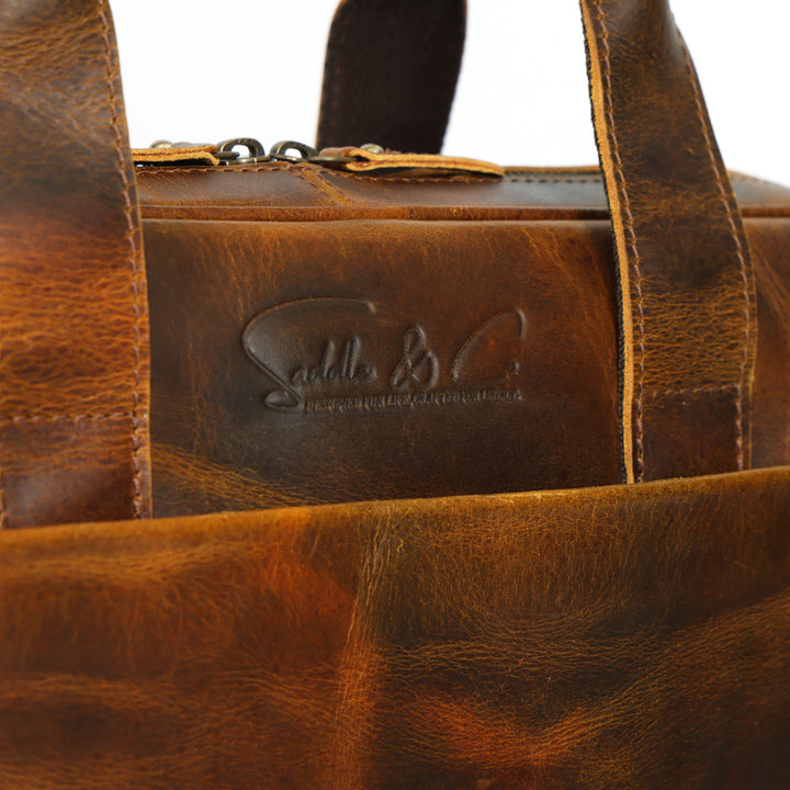 Close-up of a brown leather bag with visible branding on a white background