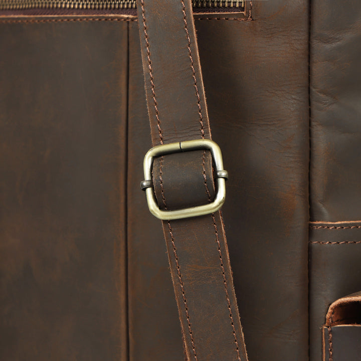 Close-up of a brown leather bag with a strap and buckle