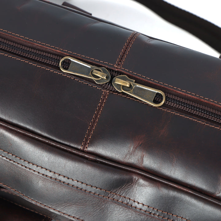 Close-up of a brown leather briefcase with gold zipper.