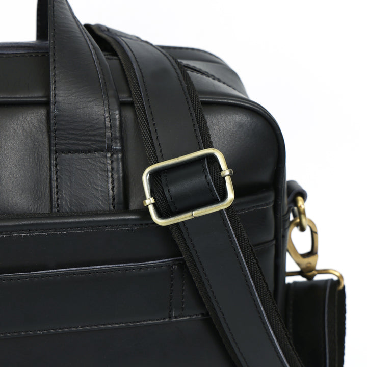 Black leather bag with gold buckle and clasp on a white background