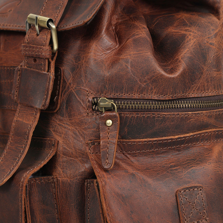 Close-up of a brown leather bag with gold zipper and buckle.