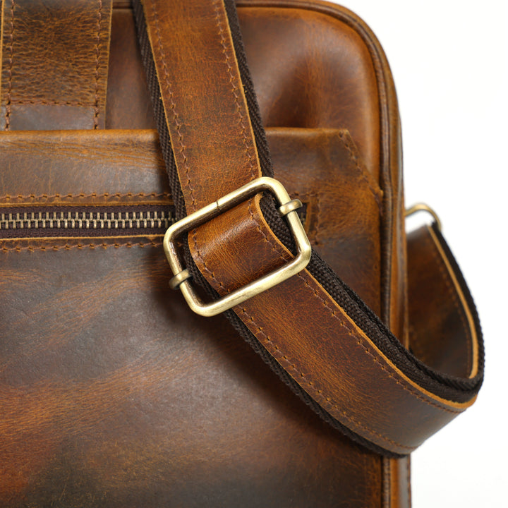 Close-up of a brown leather bag with a gold buckle on a white background