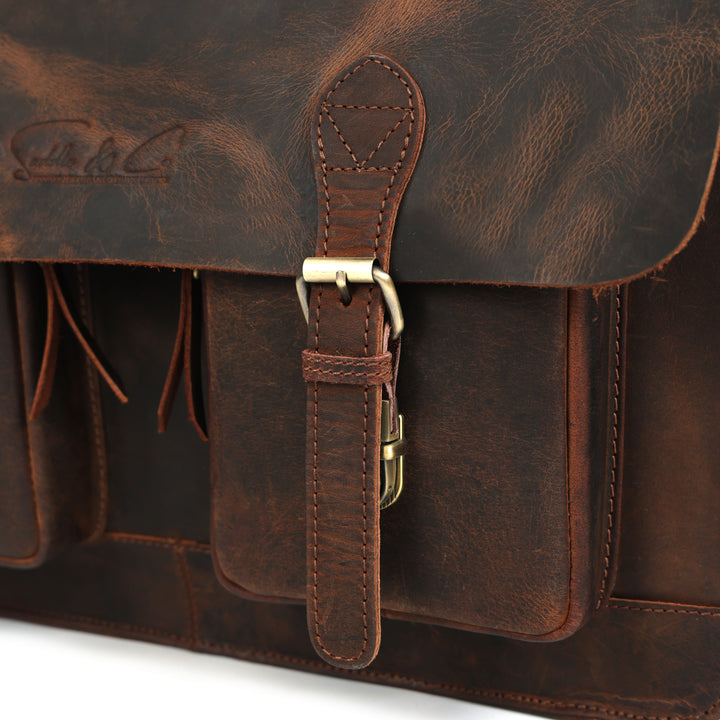 Close-up of a brown leather satchel with a strap and visible brand logo.