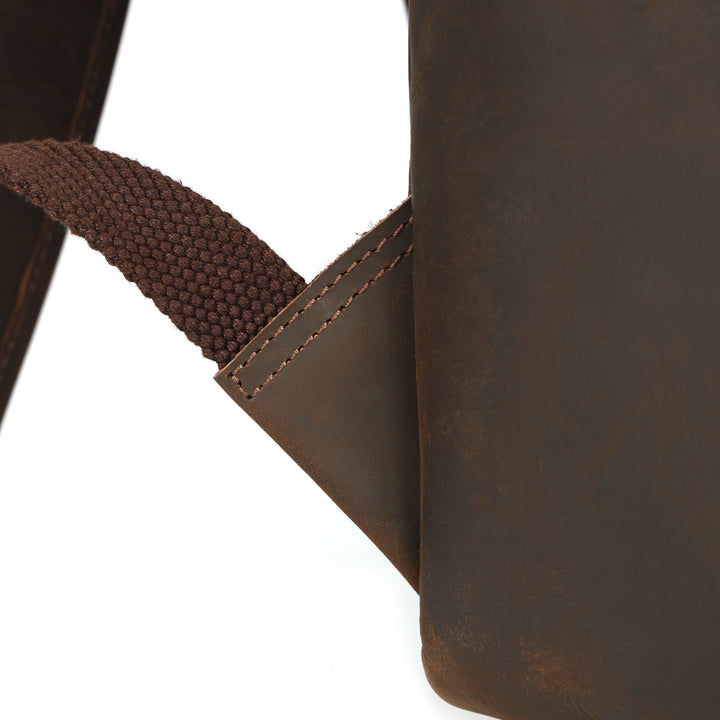 Close-up of a brown leather bag with a strap on a white background