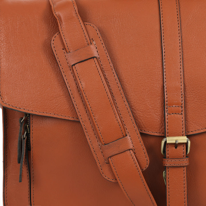 Close-up of a brown leather backpack with strap and buckle details.