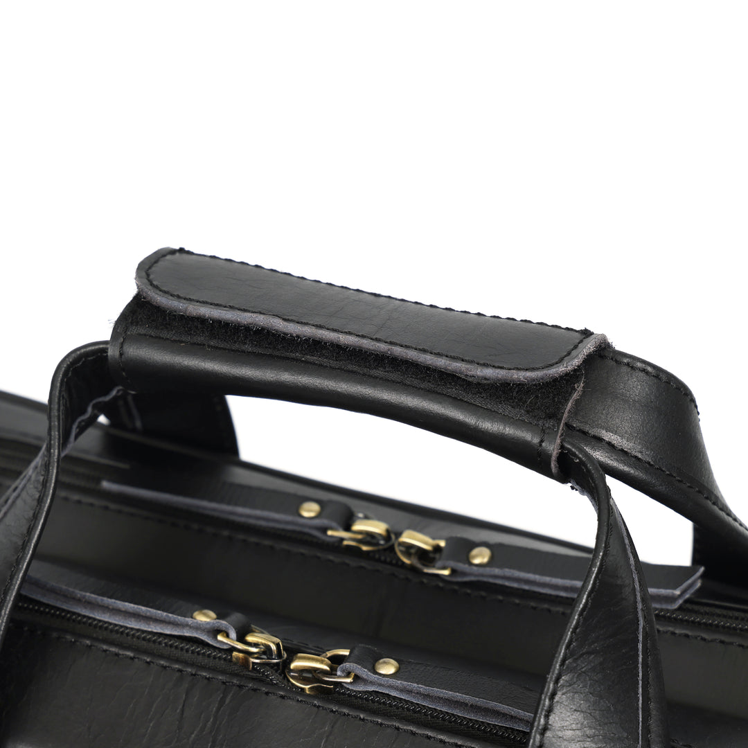 Close-up of a black leather bag with gold hardware on a white background