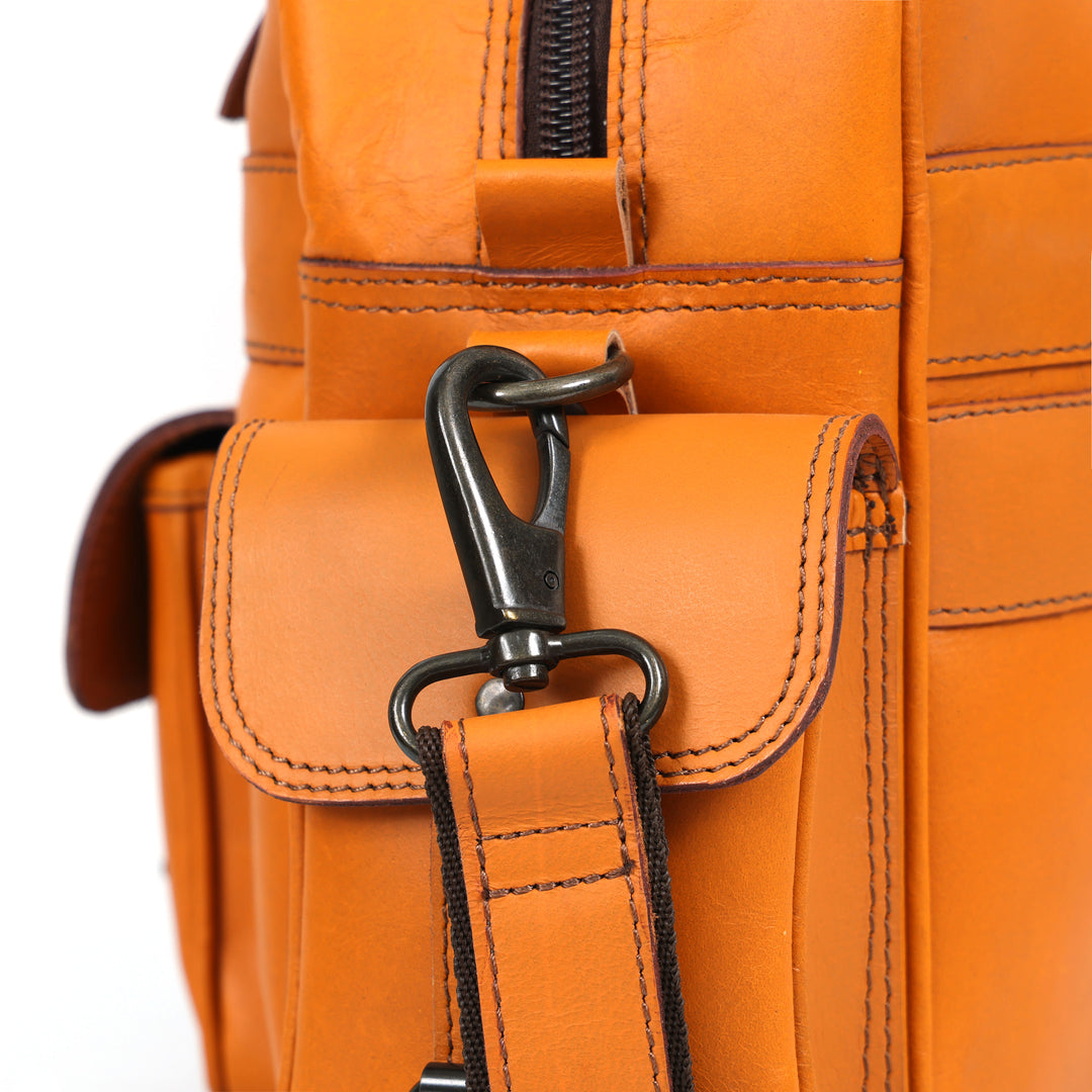 Close-up of an orange leather bag with a black zipper and strap.
