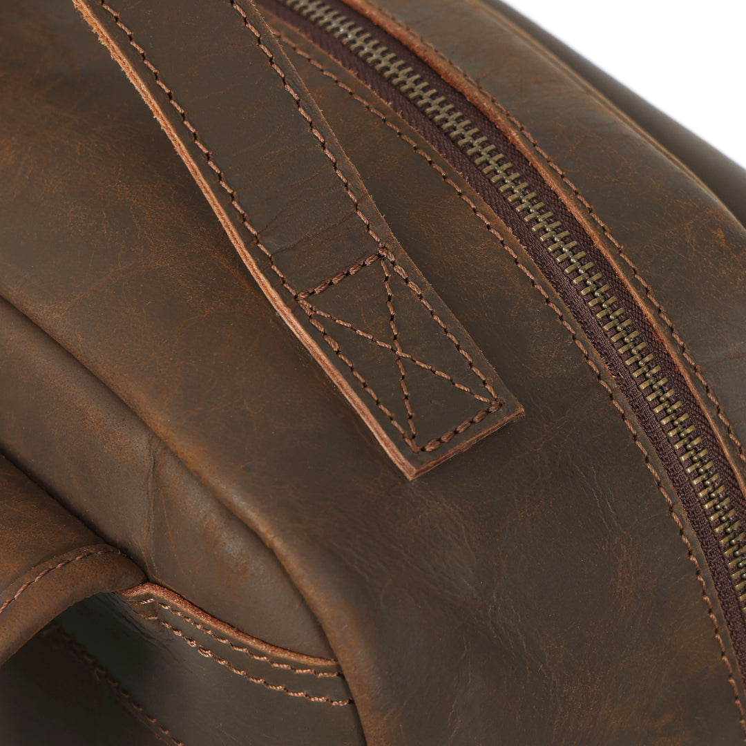 Close-up of a brown leather bag with a zipper and stitching detail.