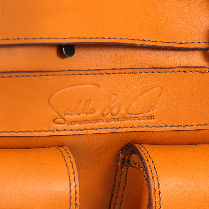 Close-up of a brown leather bag with 'Saddle & Co.' branding.