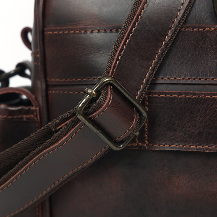 Close-up of a brown leather bag with a strap and buckle.