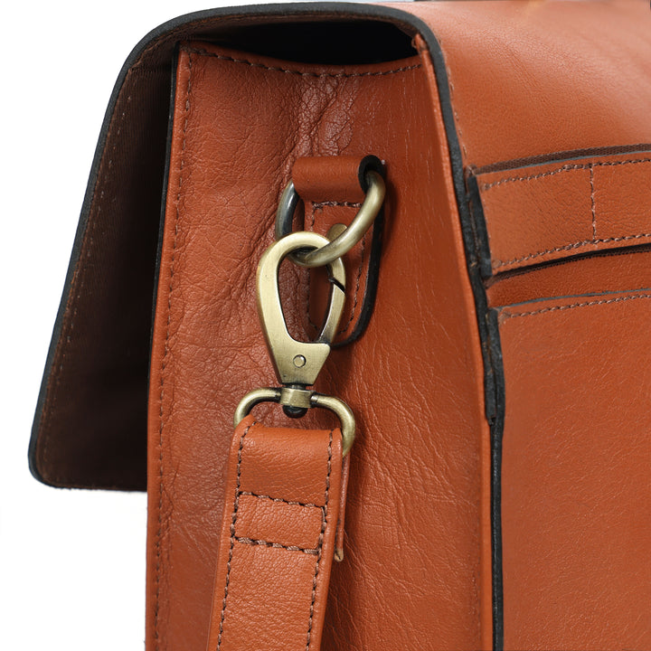 Close-up of a brown leather bag with gold hardware on a white background