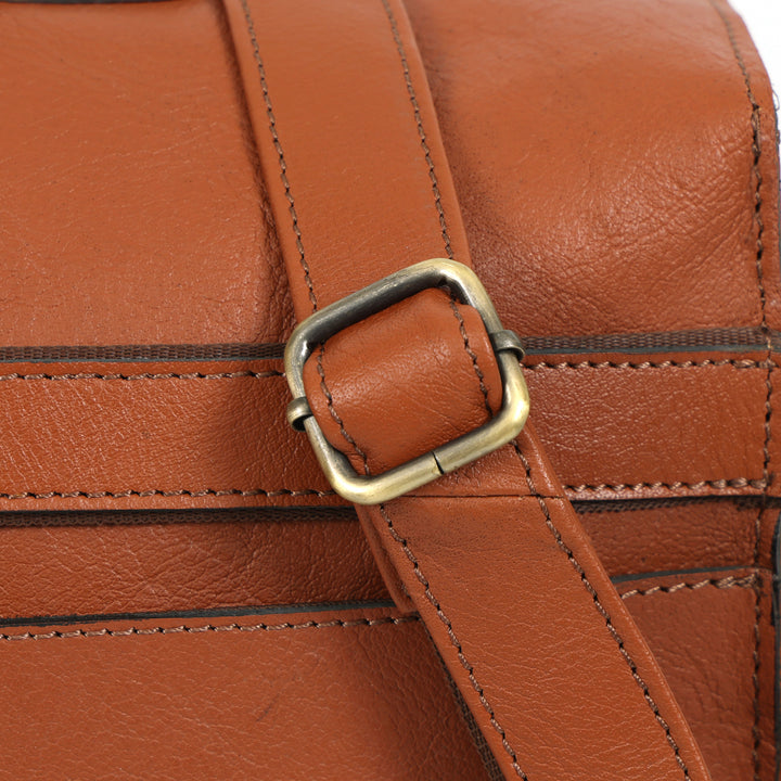 Close-up of a brown leather bag with a gold buckle.