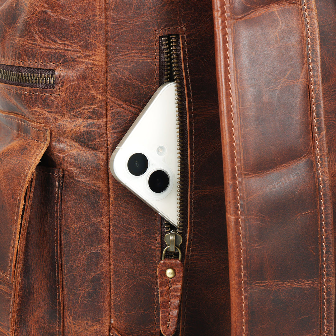 Brown leather bag with a zipper open, revealing a smartphone inside.