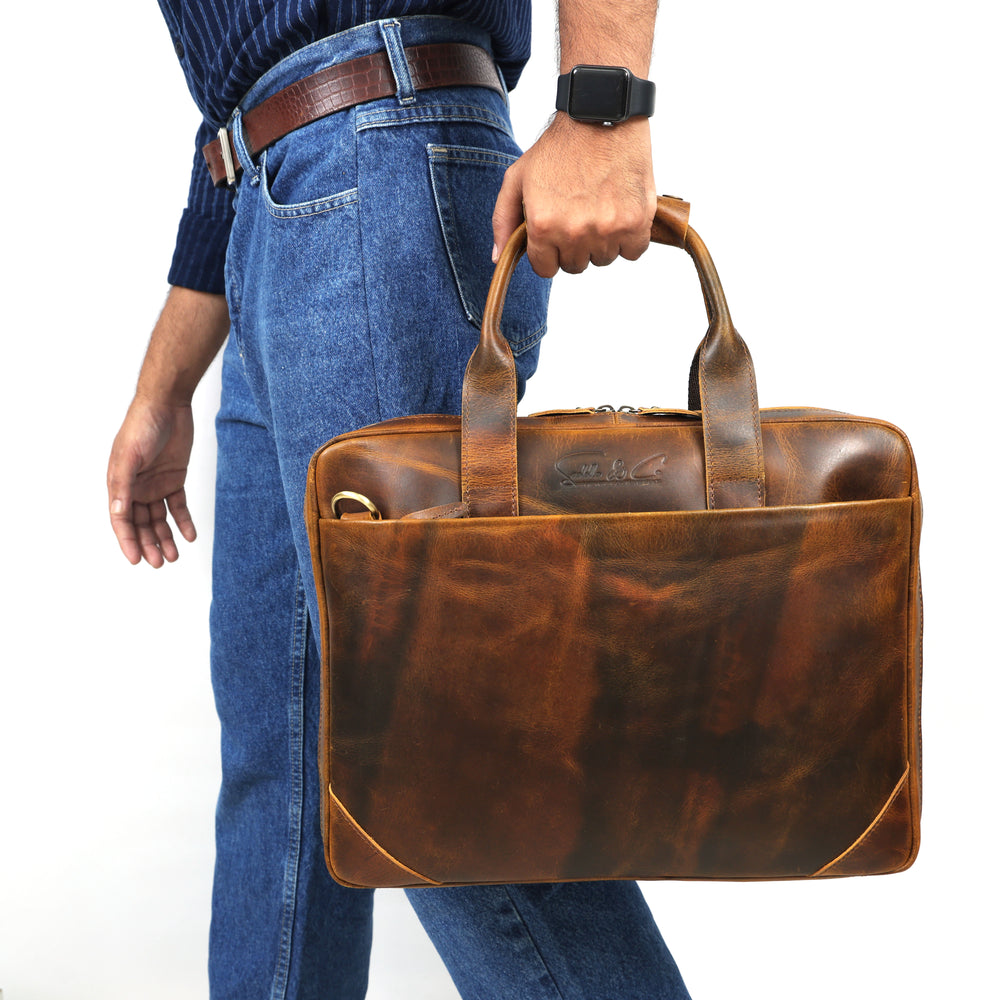 Person holding a brown leather briefcase against a white background