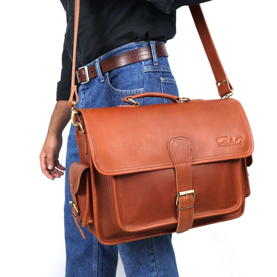 Brown leather satchel bag worn over shoulder on a plain background