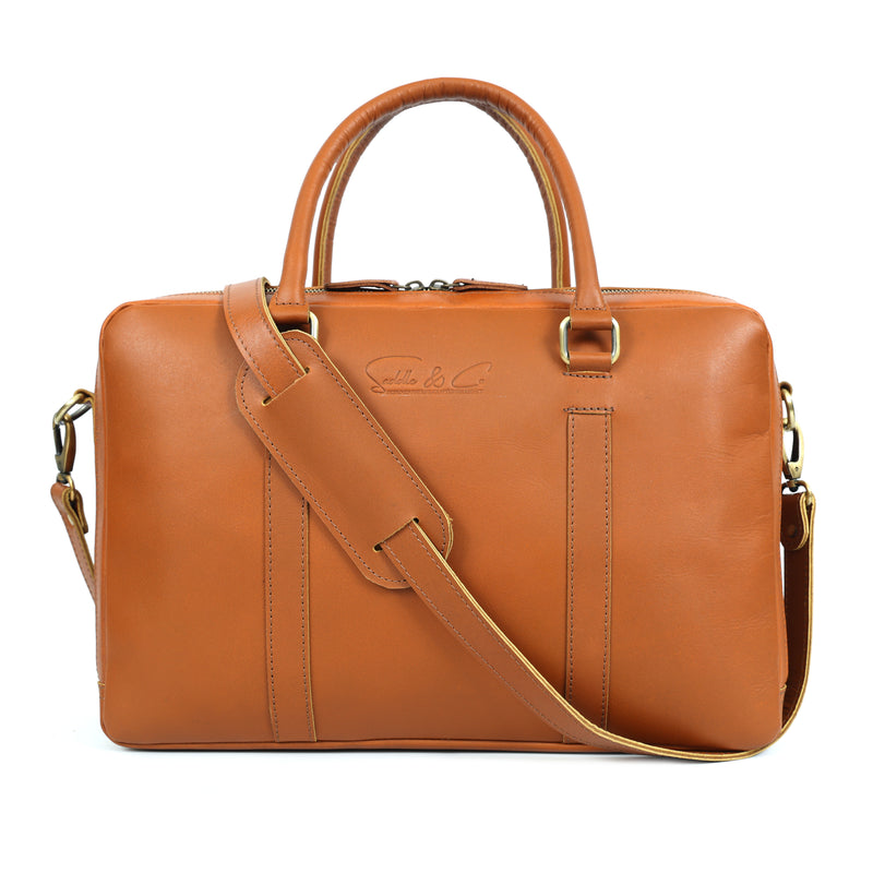 Brown leather briefcase held by a person wearing blue jeans and a brown belt.