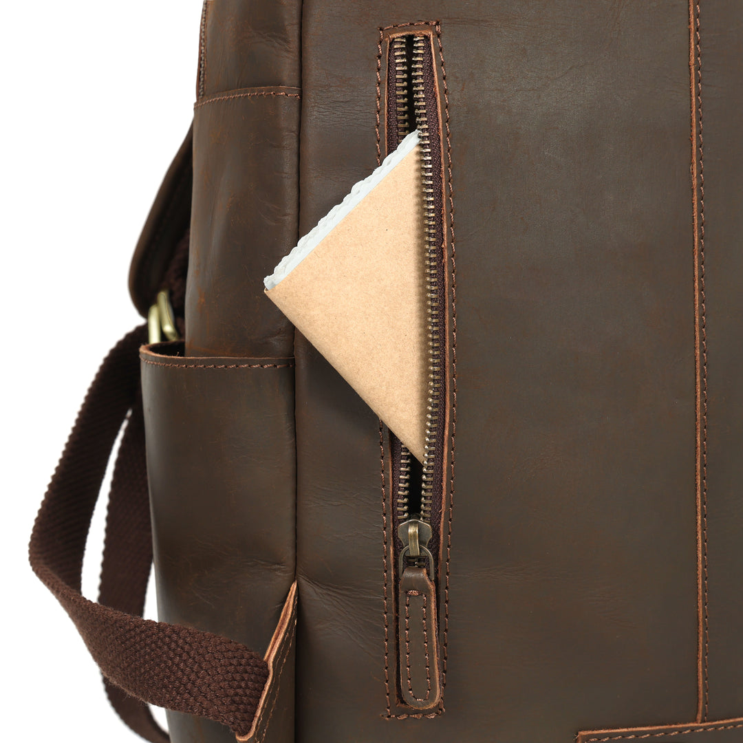 Close-up of a brown leather backpack with a zipper pocket.