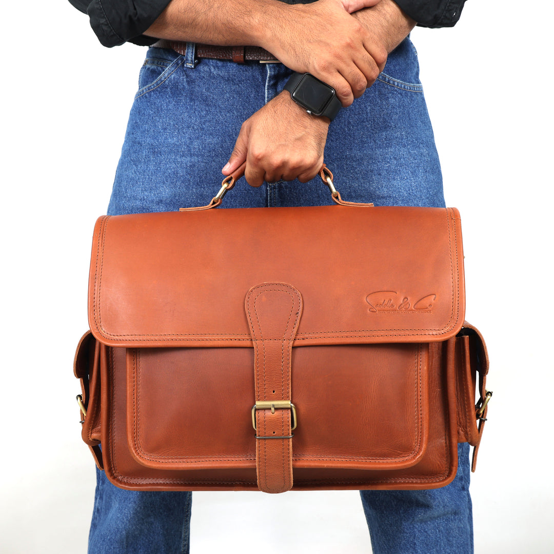 Person holding a brown leather satchel bag against a white background