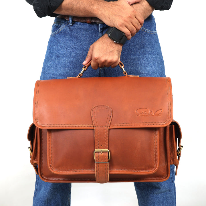 Person holding a brown leather satchel bag against a white background