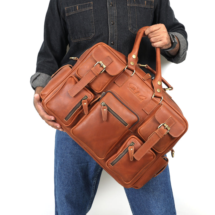 Person holding a large brown leather bag with multiple compartments on a white background