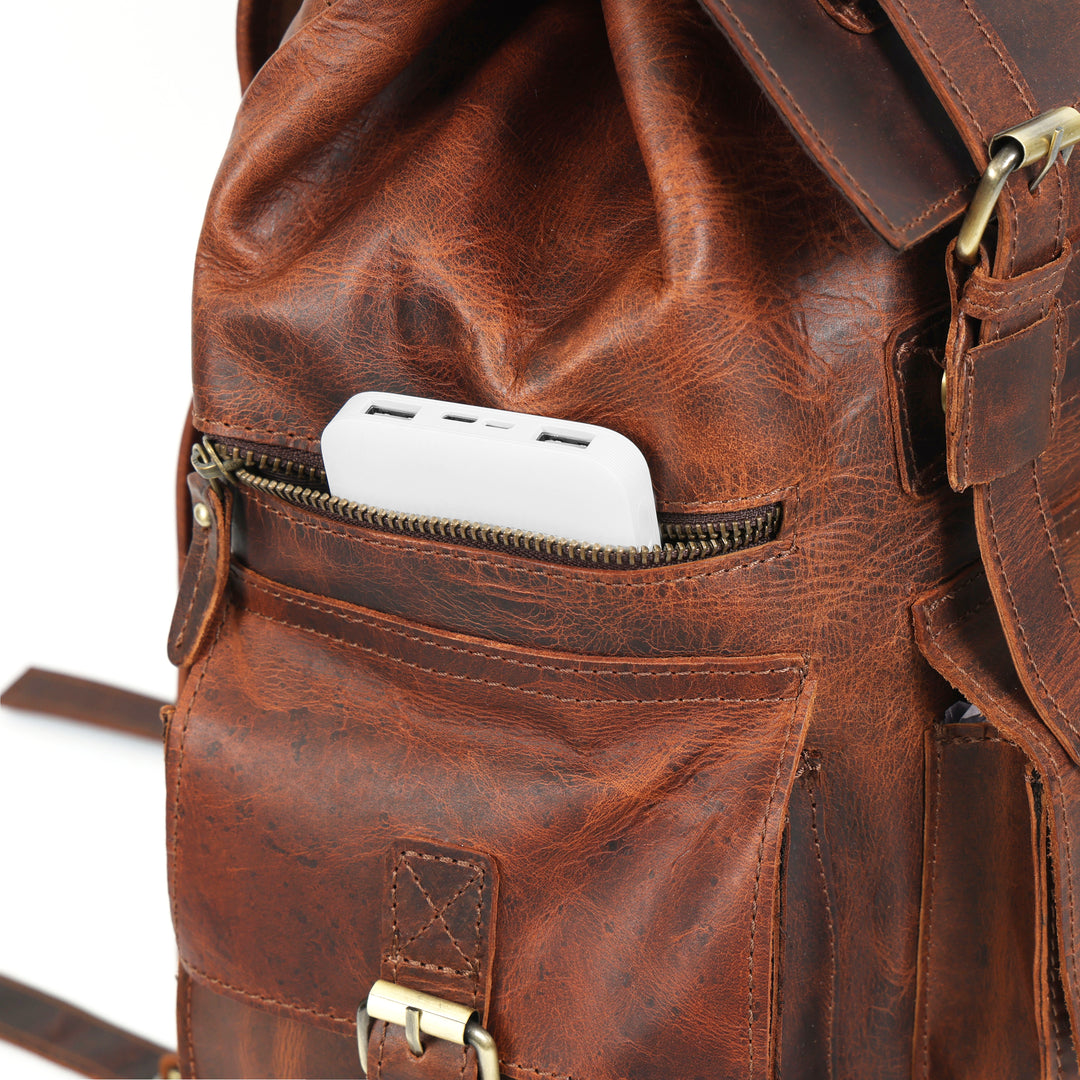 Brown leather backpack with a pocket containing a white phone on a white background