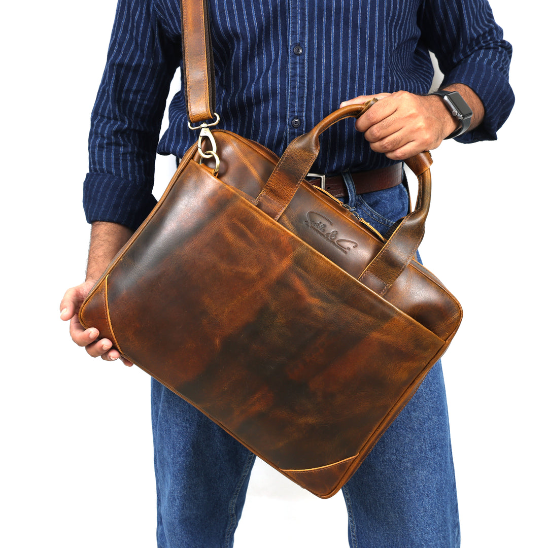 Person holding a brown leather briefcase against a white background