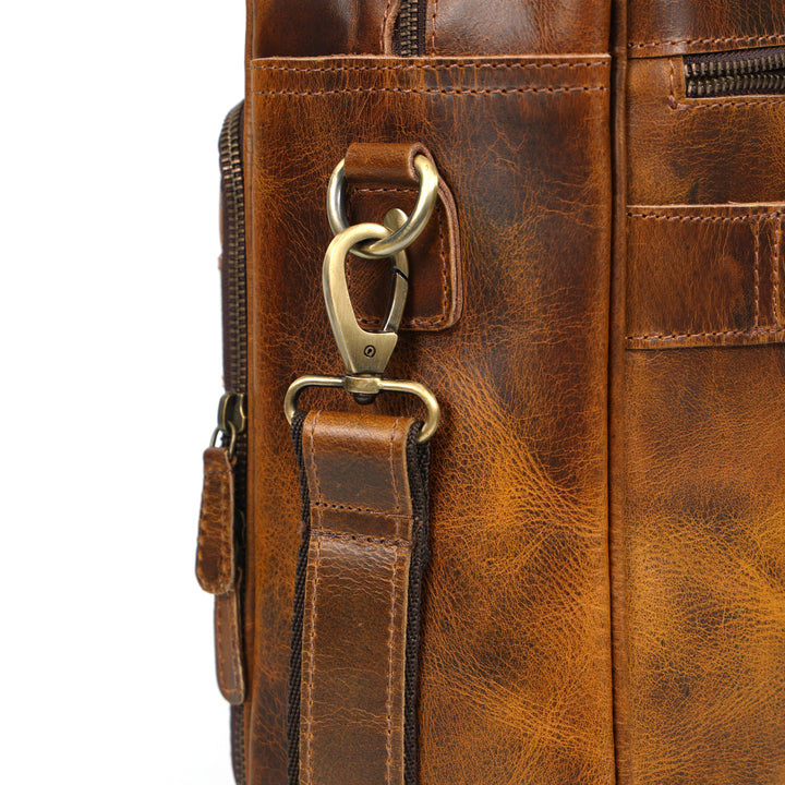 Close-up of a brown leather bag with gold hardware on a white background