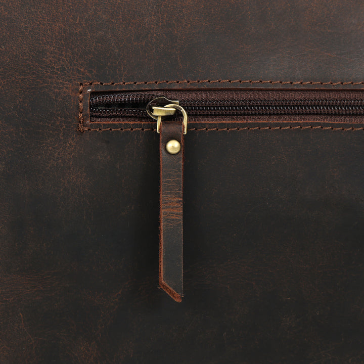 Close-up of a brown leather bag with a zipper and leather pull tab.