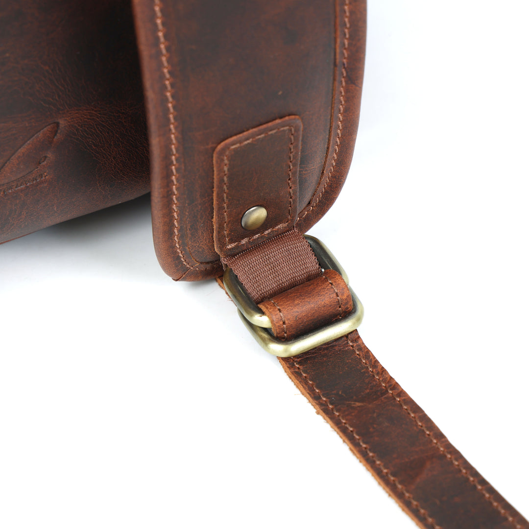 Close-up of a brown leather bag with a strap on a white background