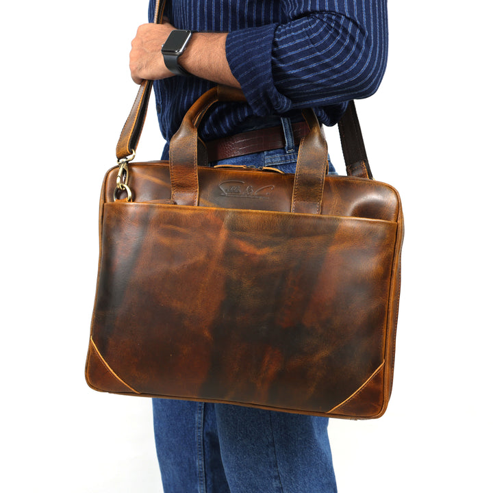 Brown leather briefcase held by a person wearing a blue striped shirt and jeans on a white background