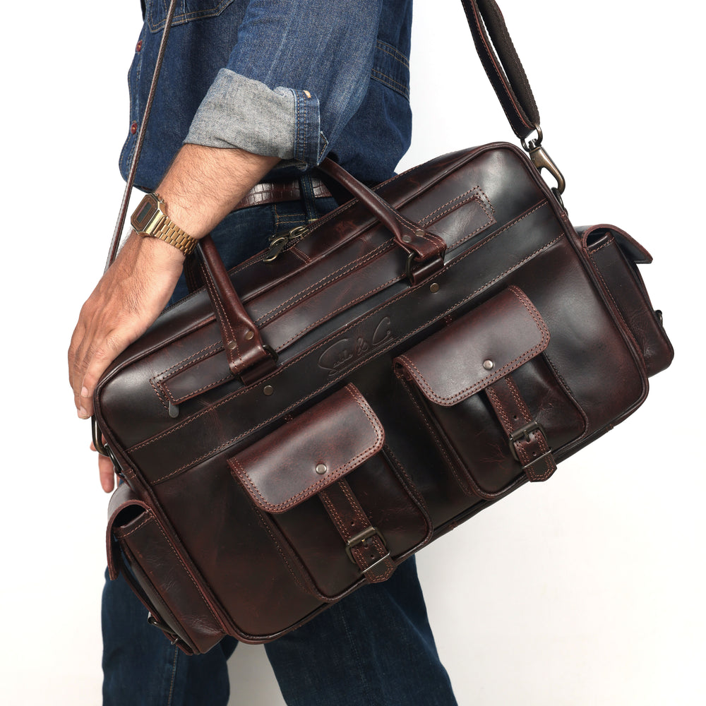 Person holding a brown leather briefcase against a white background