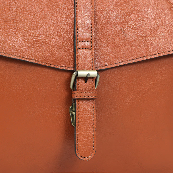 Close-up of a brown leather bag with a strap and buckle.