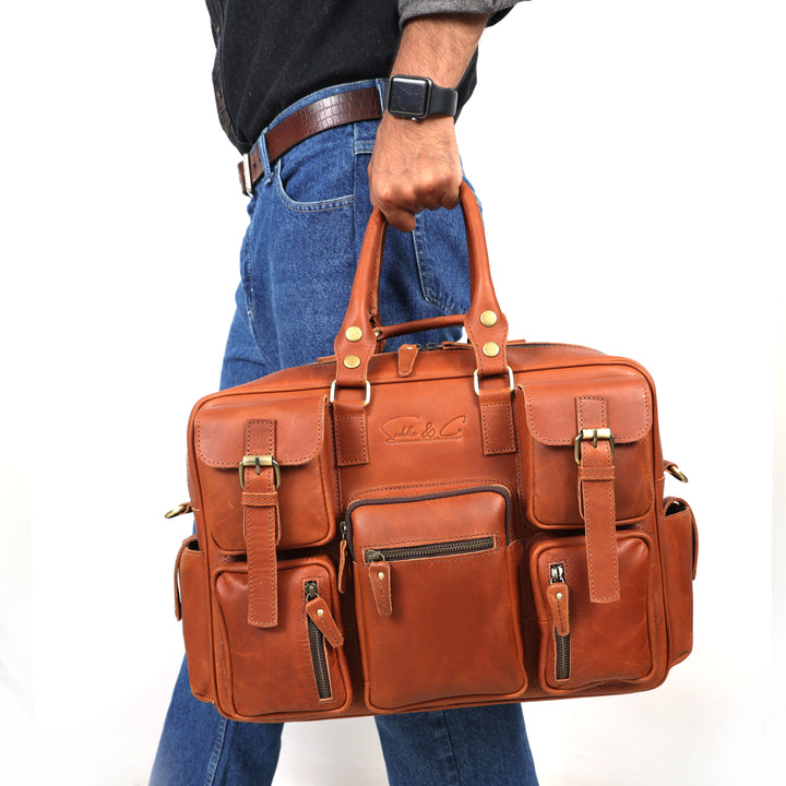 Brown leather briefcase held by a person wearing blue jeans and a black shirt.