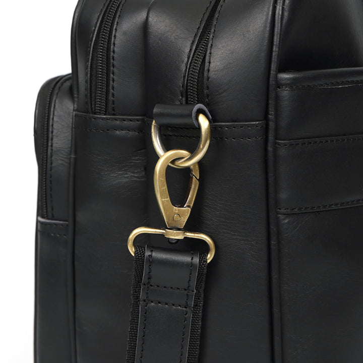 Close-up of a black leather bag with a gold clasp on a white background