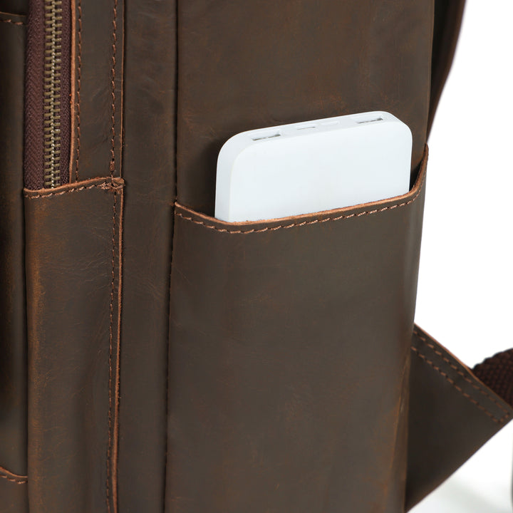Close-up of a brown leather backpack with a white phone in a pocket.