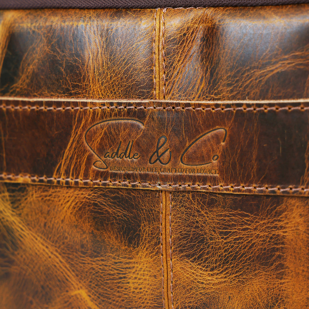 Close-up of brown leather with a brand logo, 'Saddle & Co'.