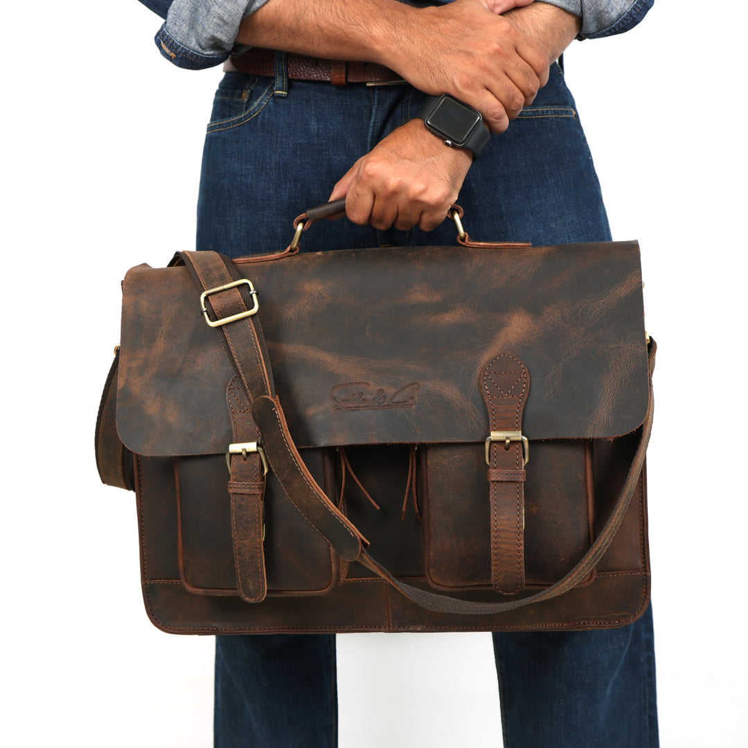 Person holding a brown leather briefcase with visible brand name on a white background