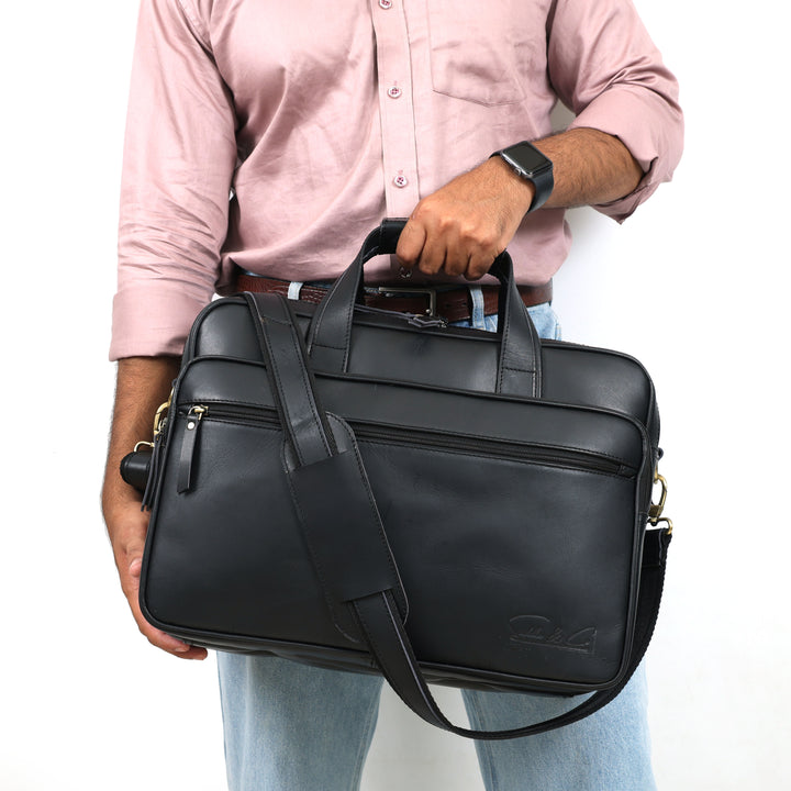 Person holding a black leather briefcase with a plain background