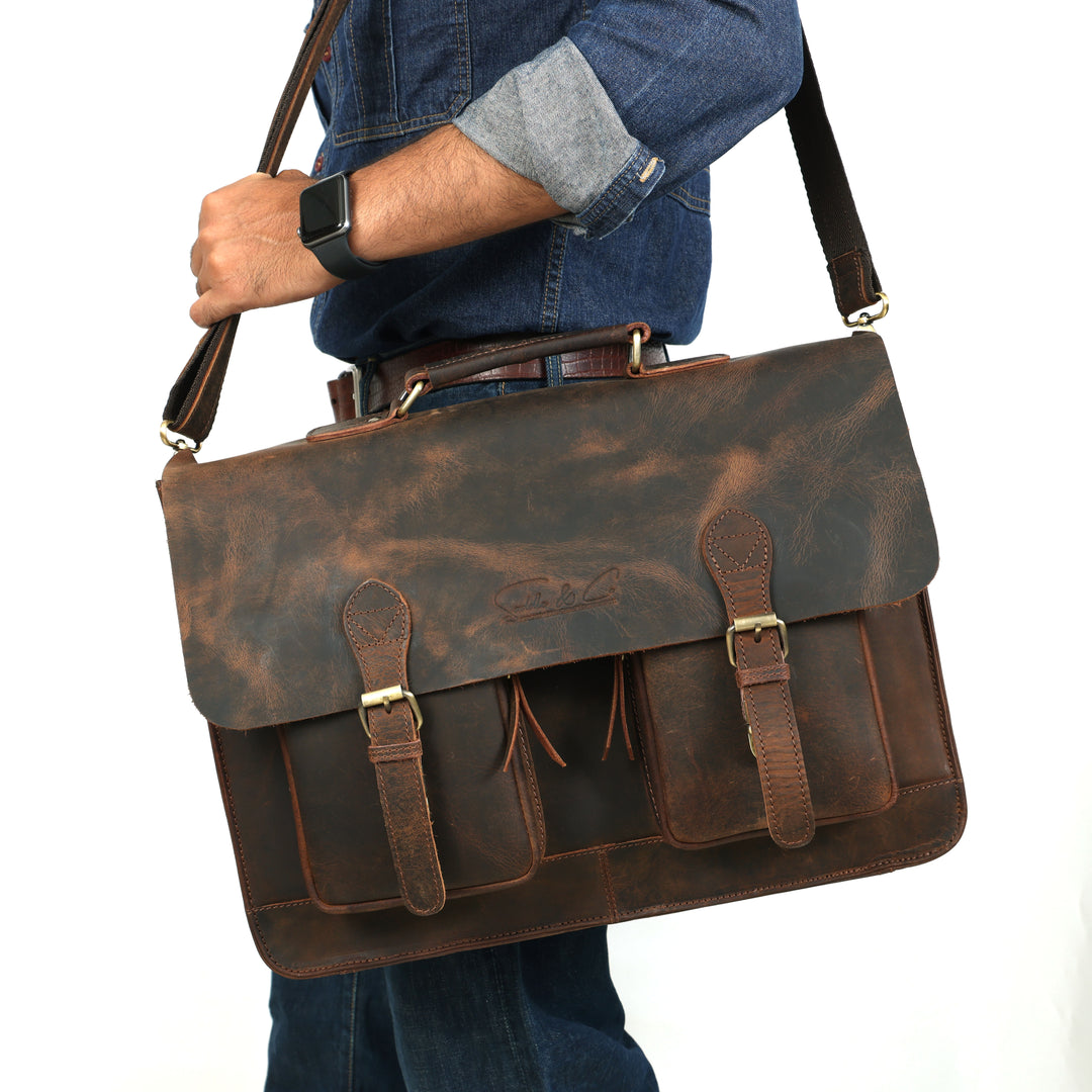 Brown leather briefcase held by a person wearing a blue shirt and jeans.
