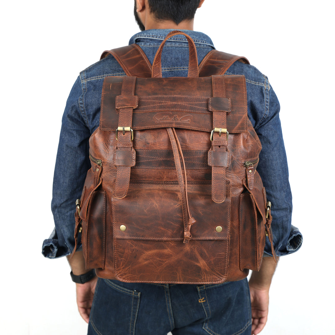 Brown leather backpack worn by a person on a white background